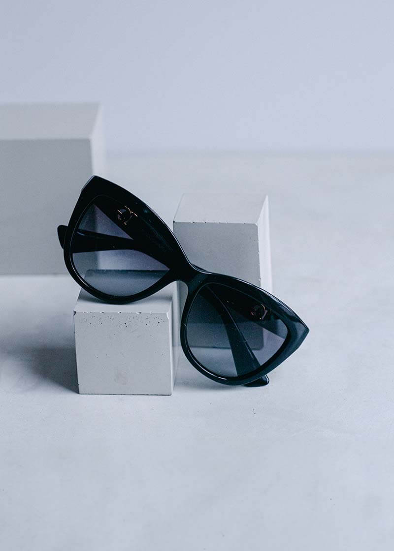 Black cat-eye sunglasses propped on grey concrete blocks